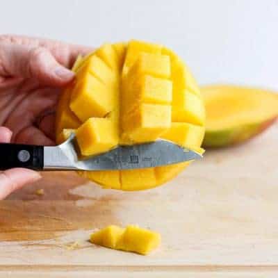 Illustrating the knife method for removing the mango from the skin