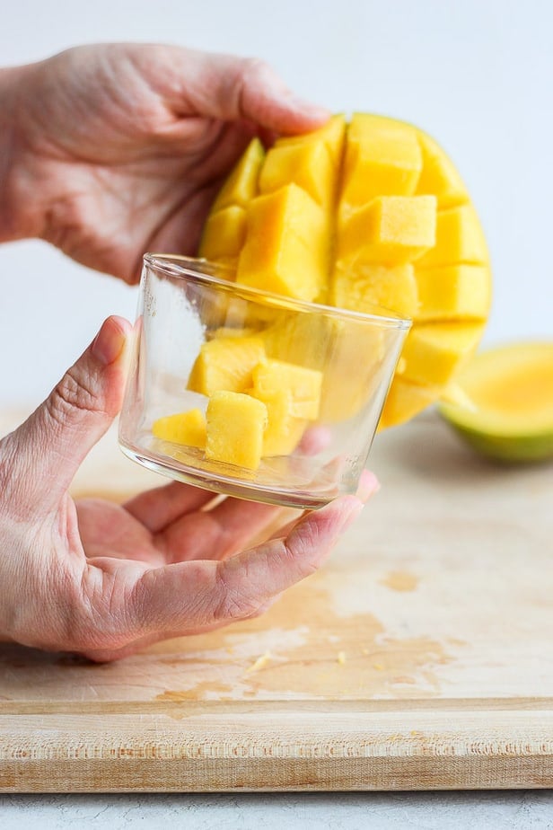placing cut mango cubes into glass