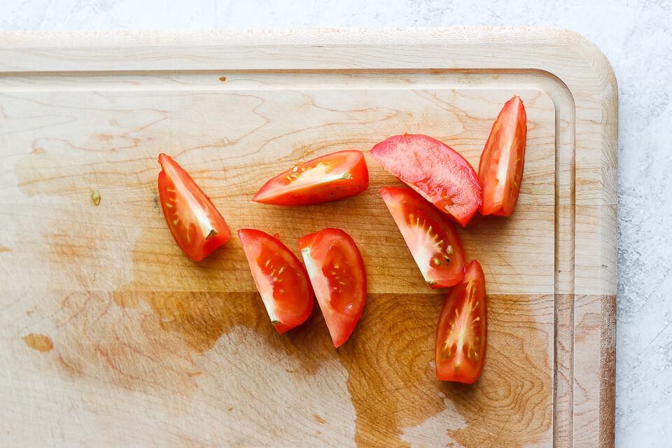 Tomato wedges on a cutting board. 