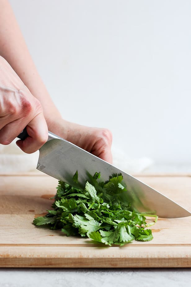 chopping cilantro on a wooden chopping board