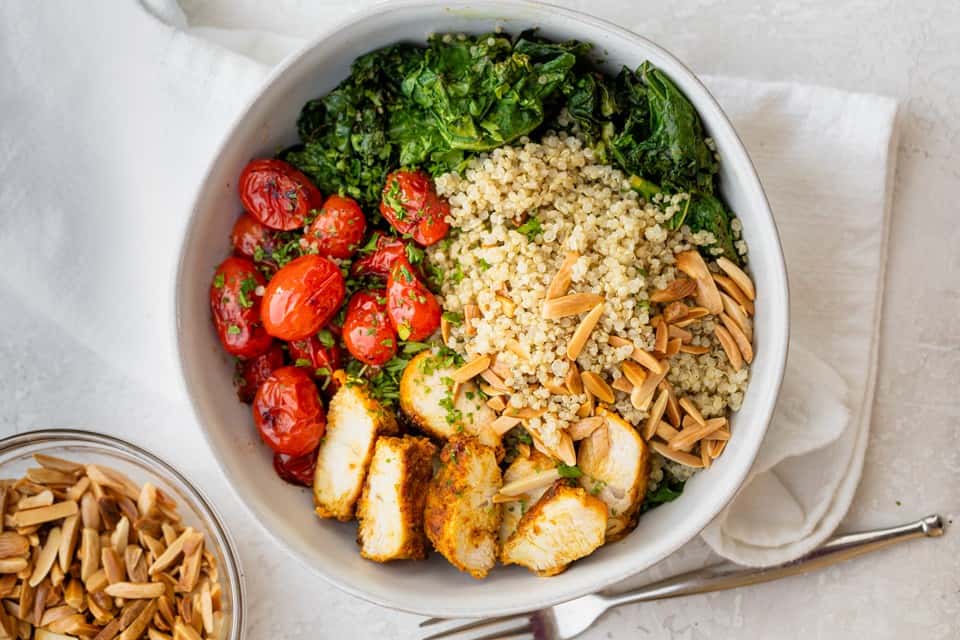 Chicken and quinoa bowl in a large serving bowl with toppings.