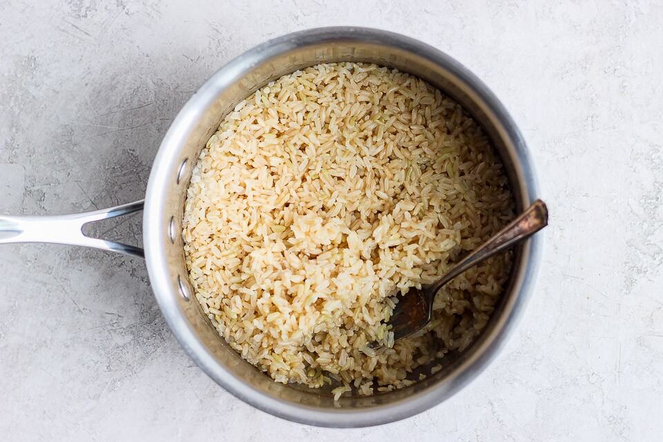 A spoon in a pot of cooked brown rice.