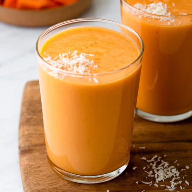 Mango papaya smoothie in a glass with another in the background.