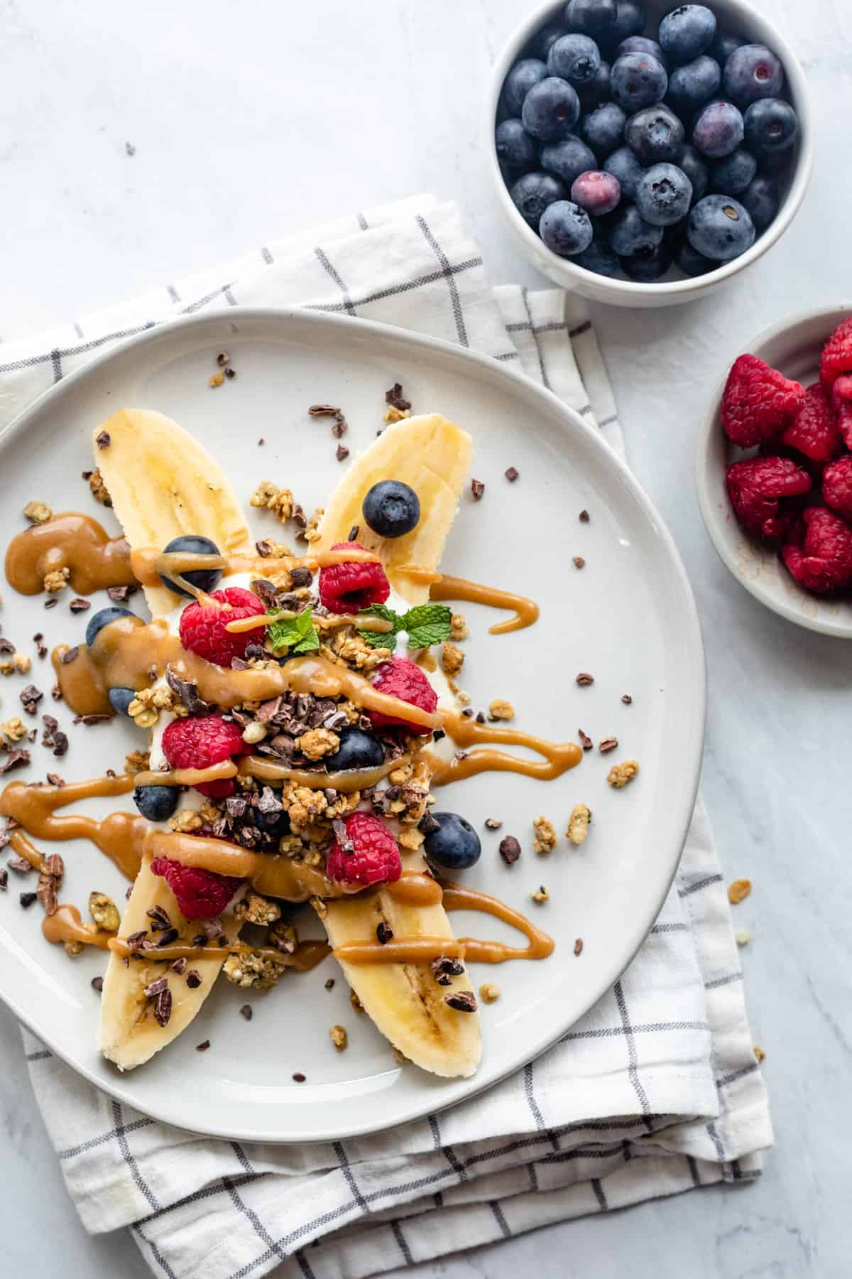 Healthy banana split topped with yogurt, fruit and granola