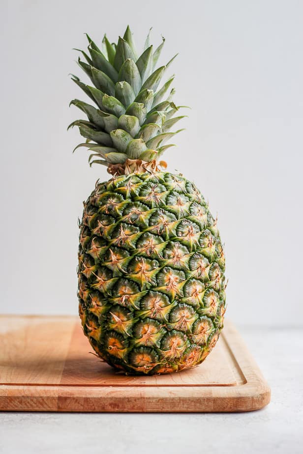 Large uncut pineapple on a cutting board