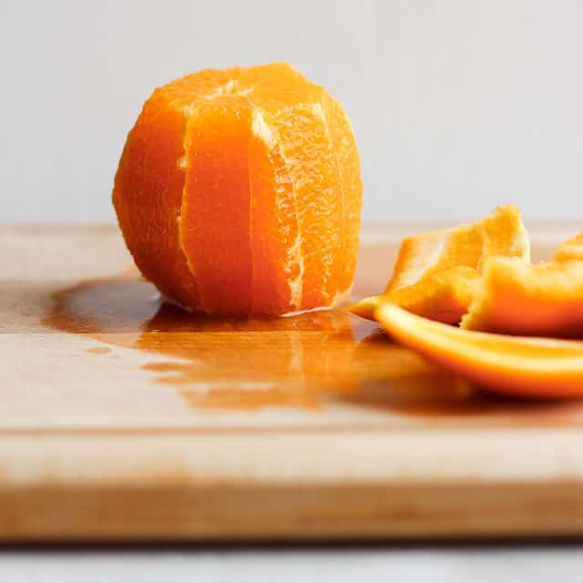 Peeled orange on cutting board with peels on the side