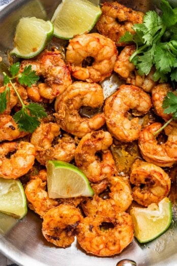 Chili lime shrimp in a pan with garnish and lime.