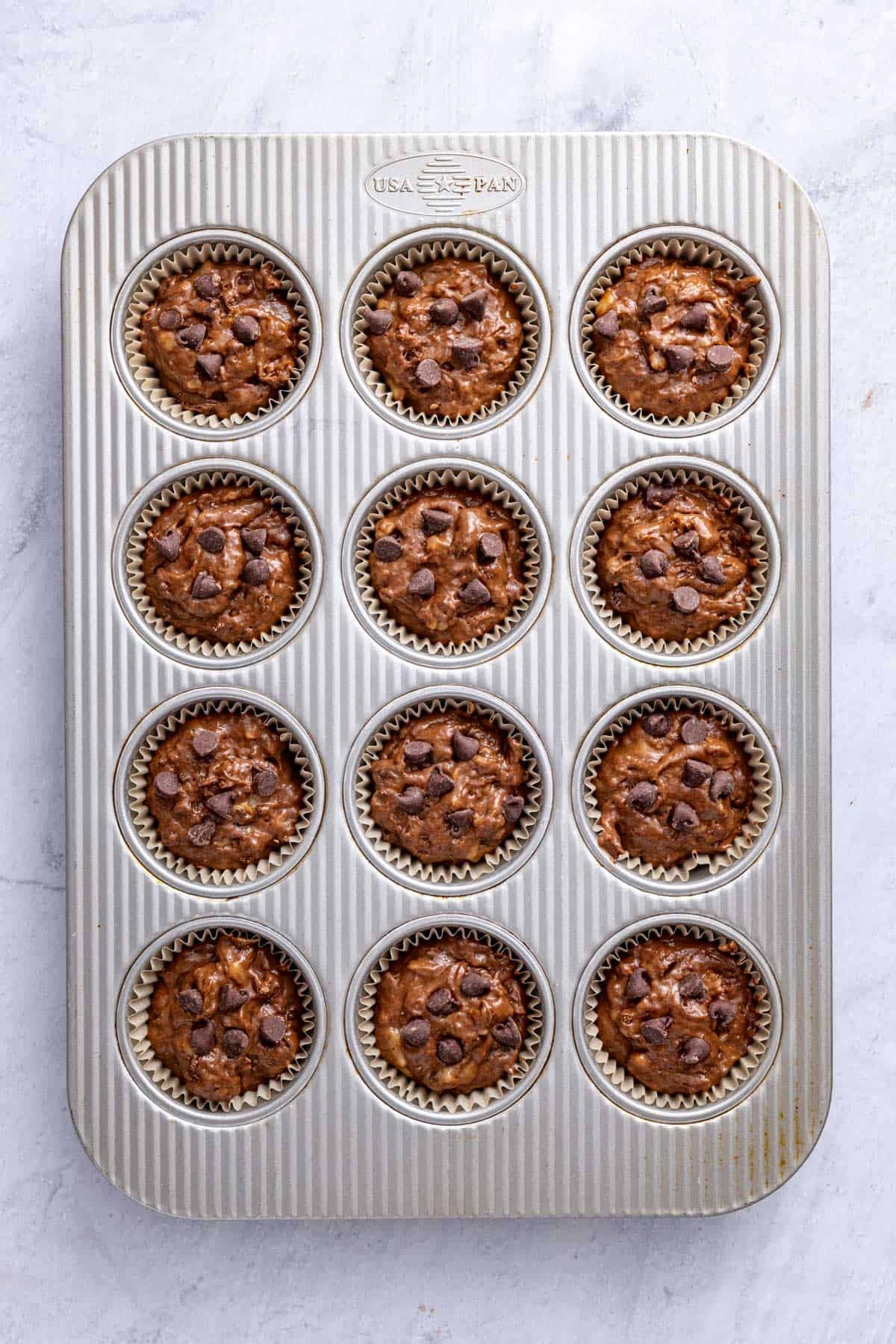 Batter in prepared muffin pan with a few extra chocolate chips on top before baking.