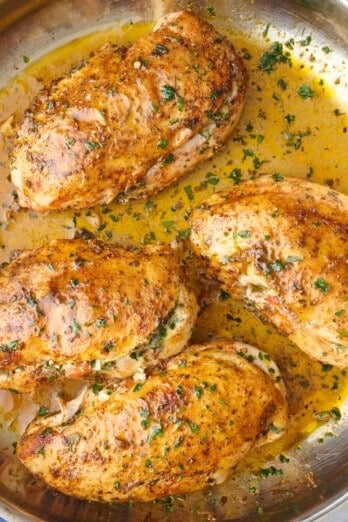 Stuffed chicken in the skillet garnished with chopped parsley.