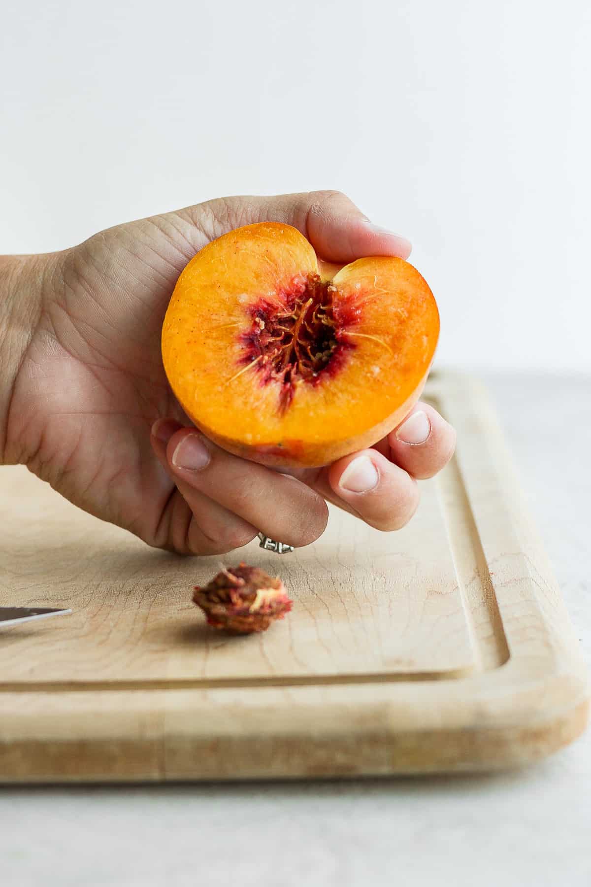 Half peach cut with pit on the cutting board