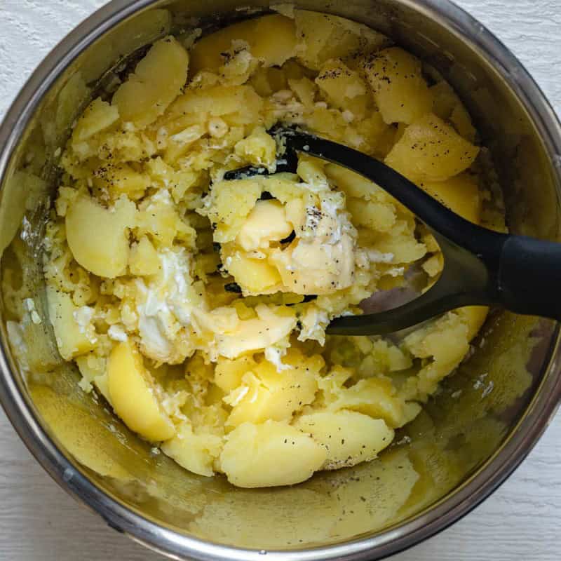 Potato masher mashing the mashed potato ingredients together.