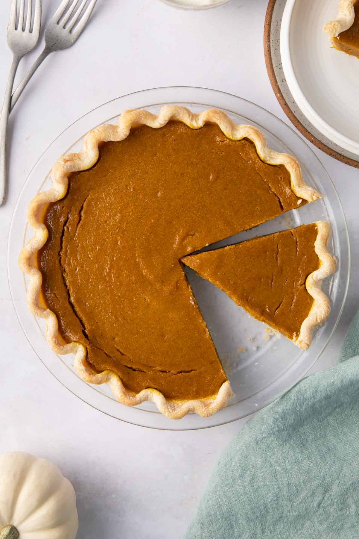 Pumpkin pie with slices cut out on a round glass baking dish