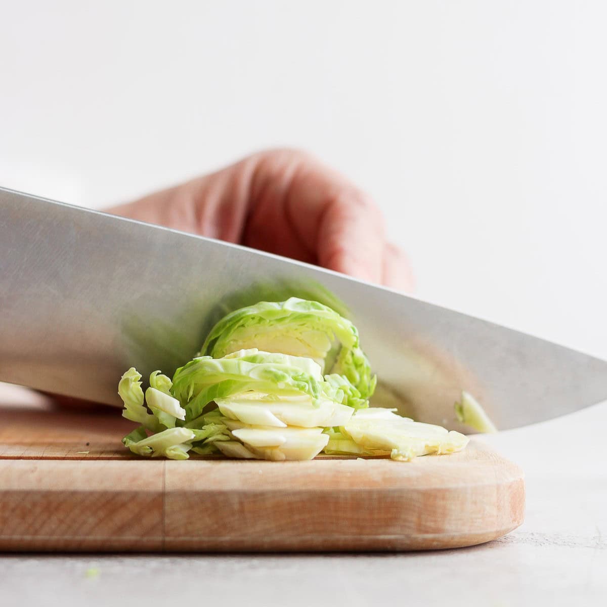 Brussel sprout lengthwise on a cutting board being sliced.