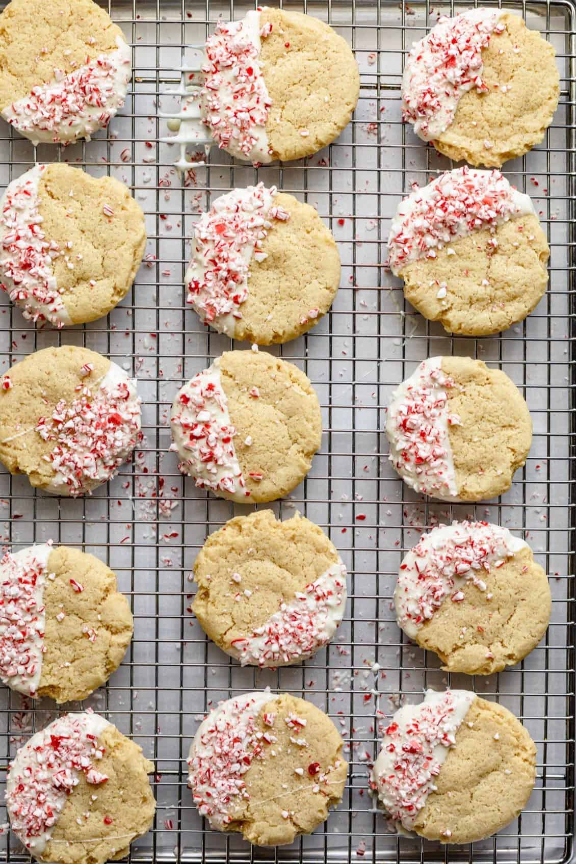 Cookies on a wired rack after dipping them in the icing and adding the peppermint pieces.