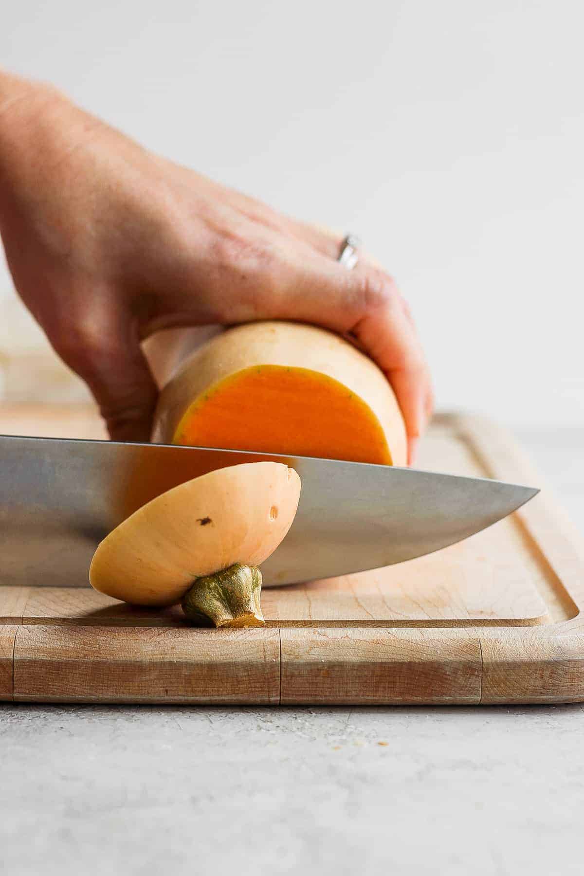 Butternut squash on cutting board getting cut