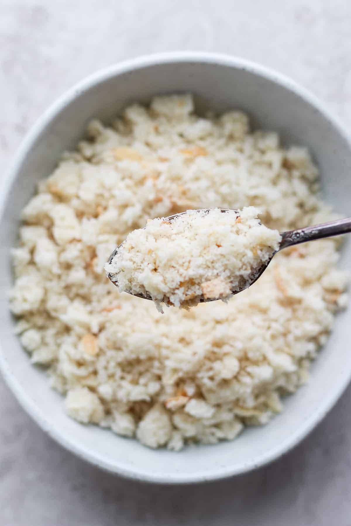Spoonful of homemade breadcrumbs over bowl of breadcrumbs