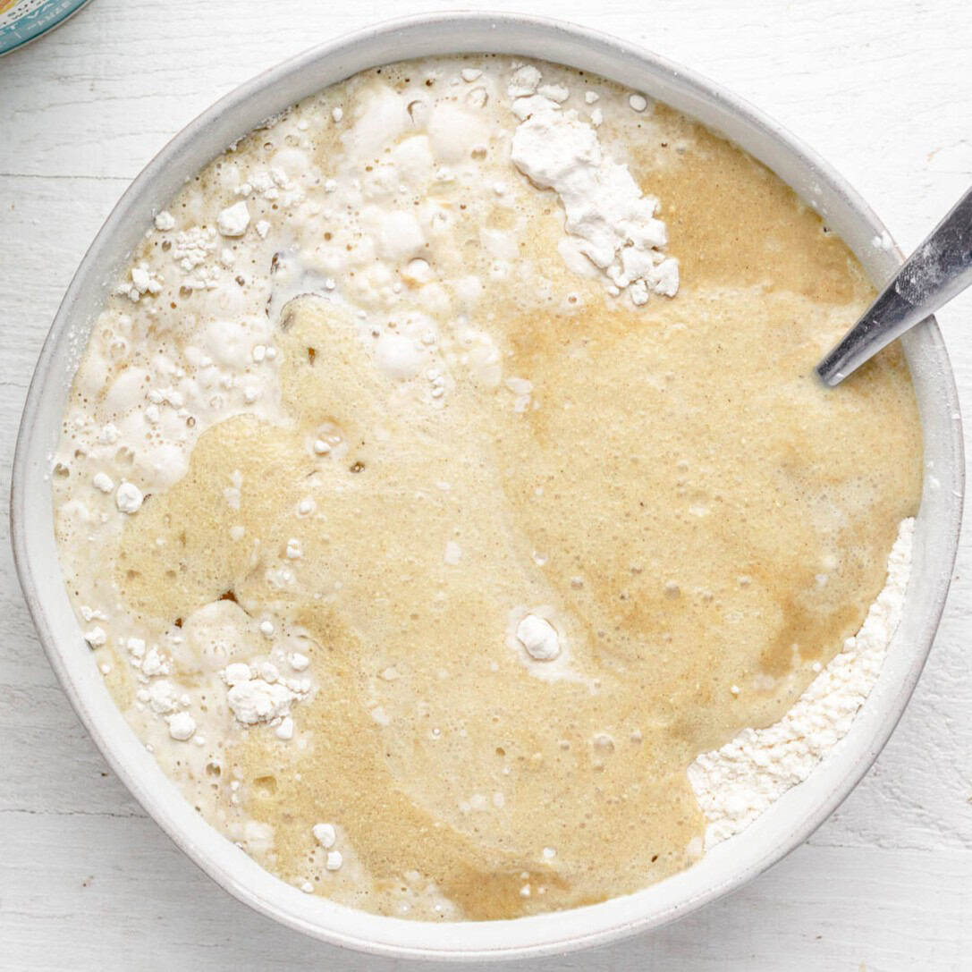 Flour, cornstarch and sugar, milk, oil and protein powder in a bowl before mixing.
