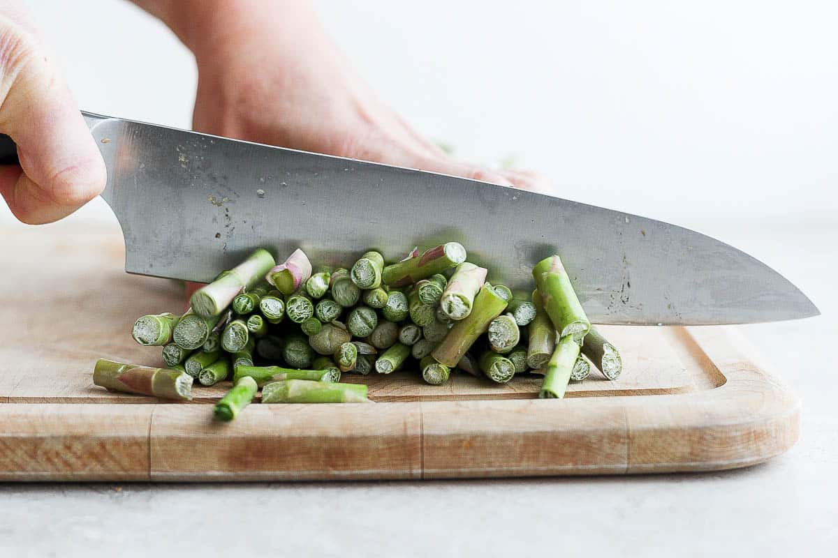 Cutting ends off asparagus on cutting board