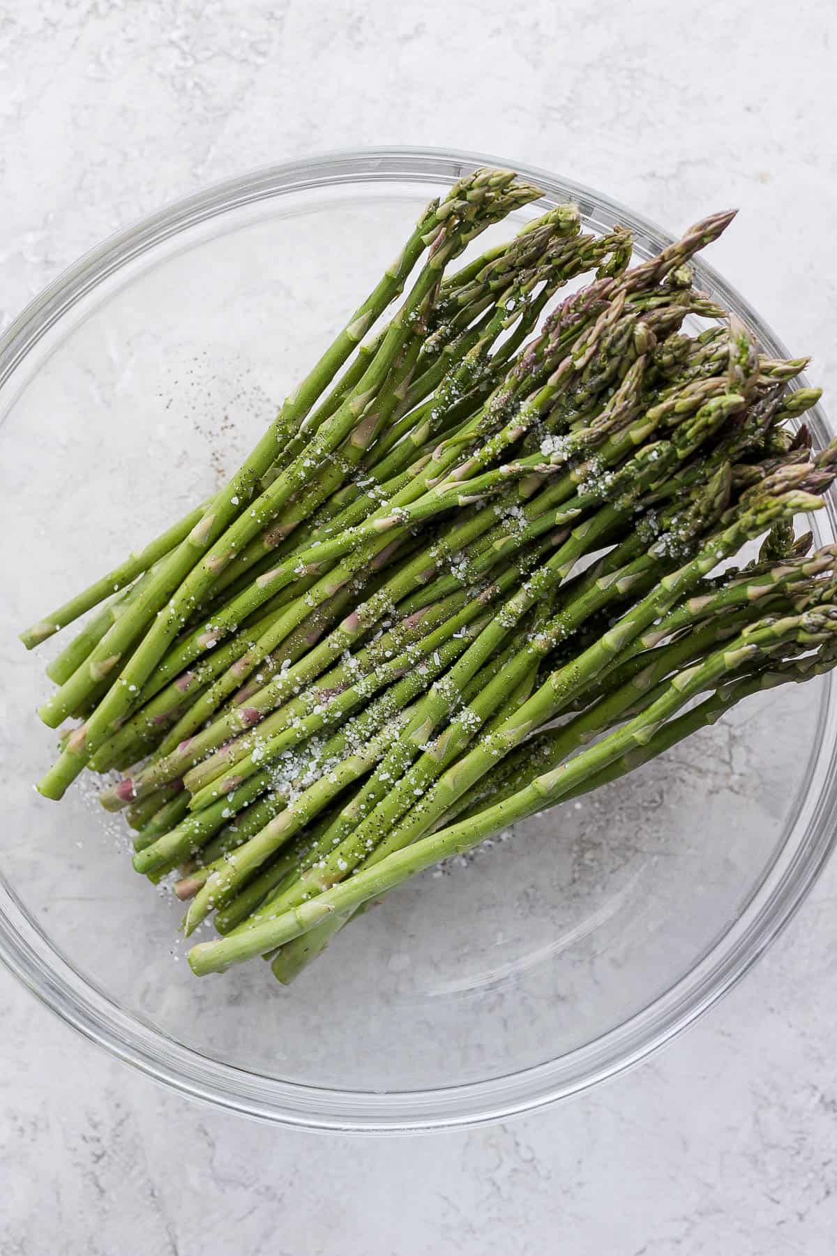 Tossing asparagus with olive oil, salt and papper
