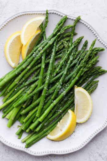 Boiled asparagus on a plate with lemon wedges