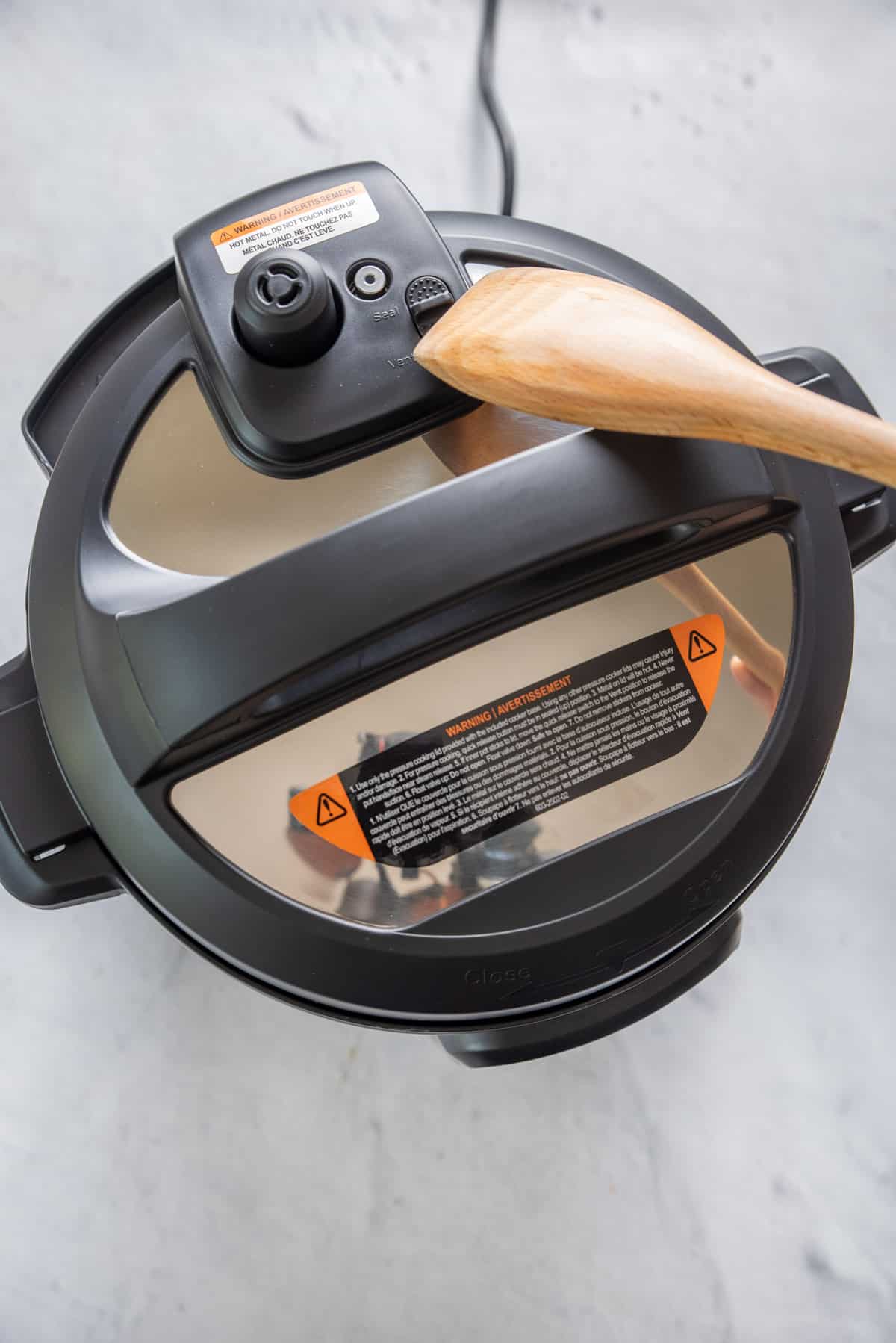 Wooden spoon being used to seal and vent the instant pot