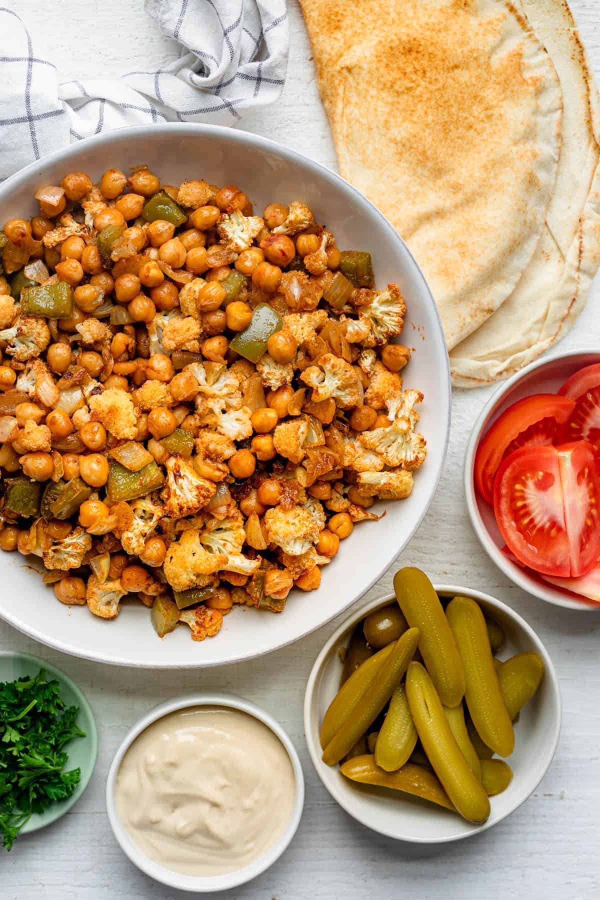 Oven roasted chickpea shawarma in a bowl with toppings surrounding.