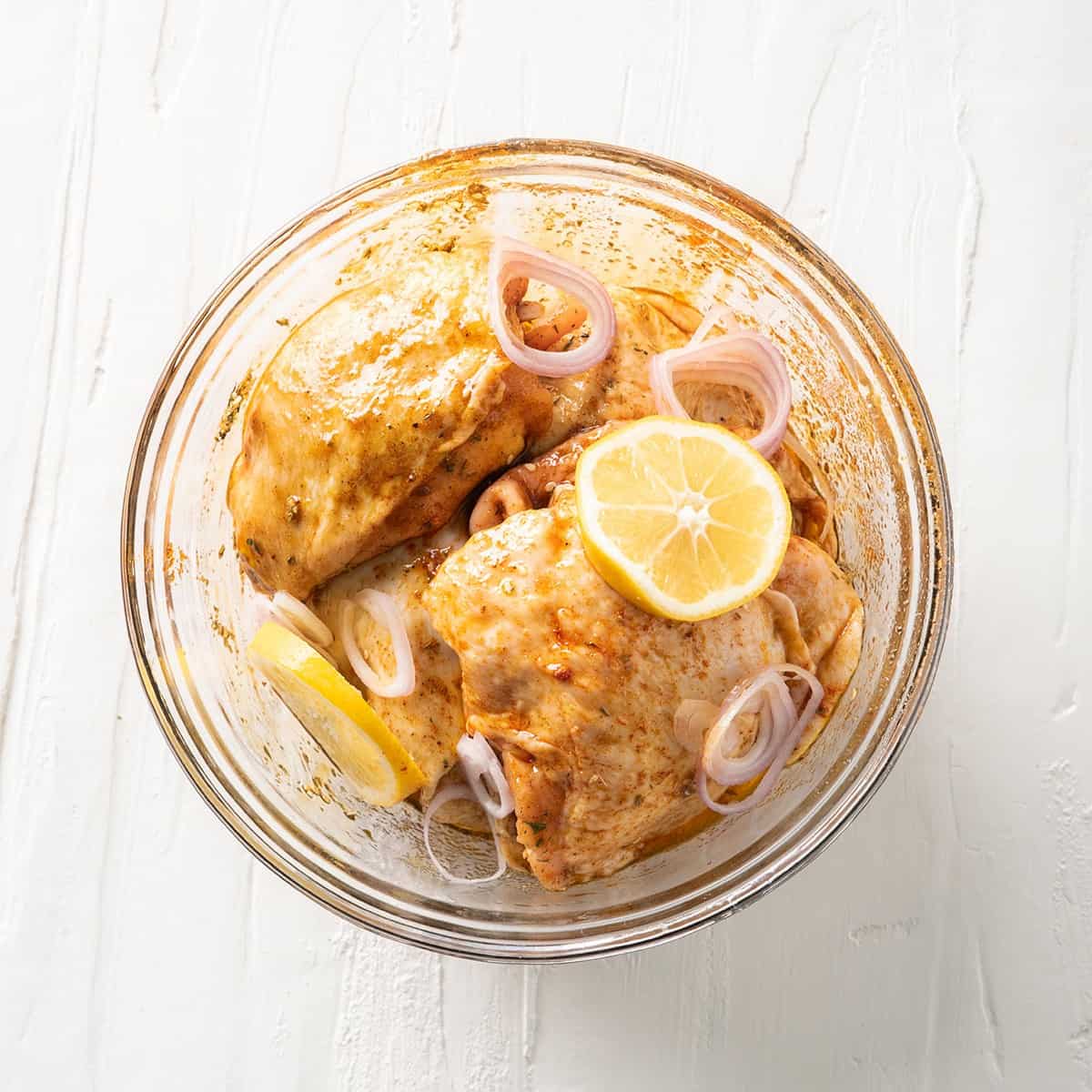 Shallots and lemon slices added on top of the chicken.
