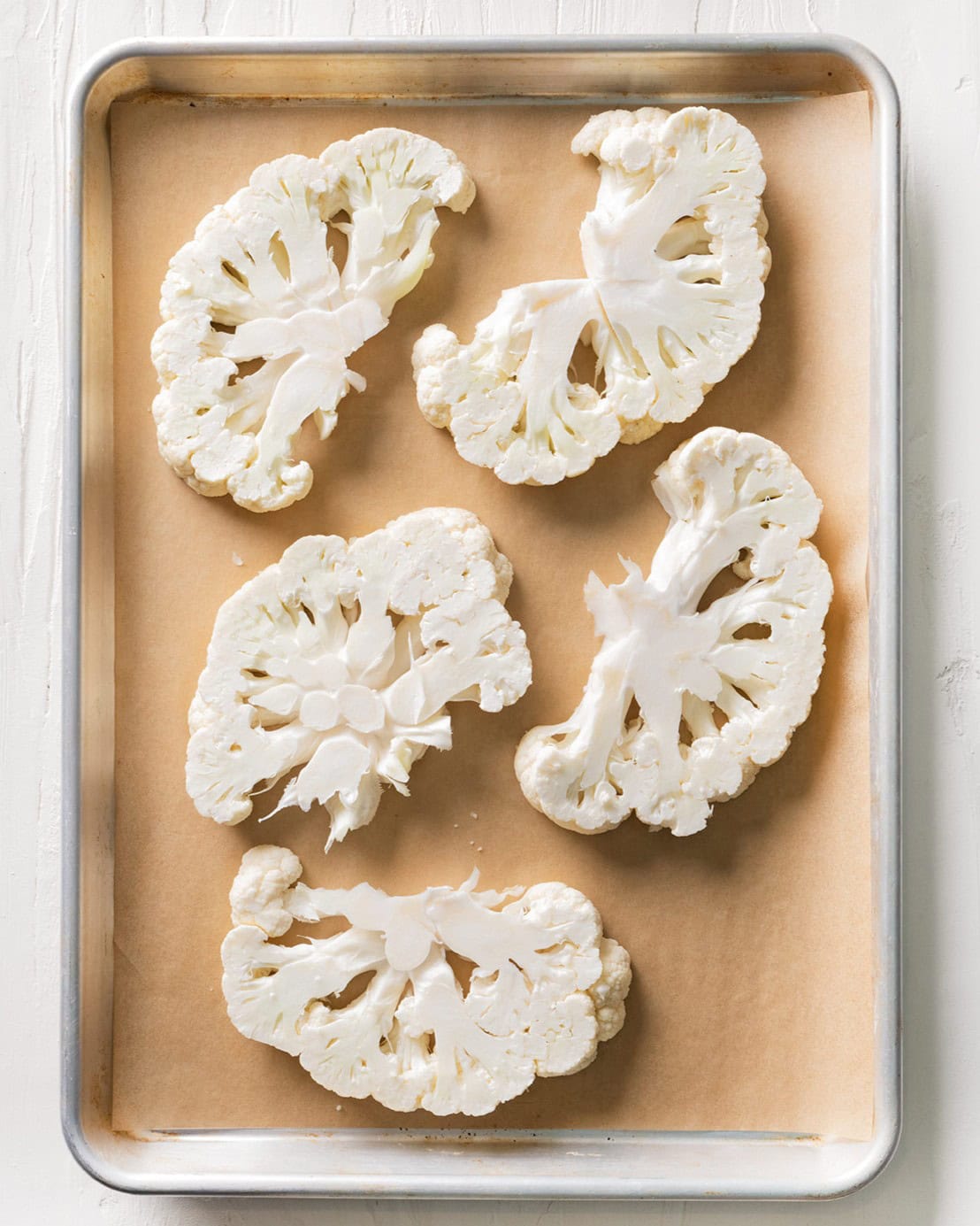 Sliced cauliflower on a baking sheet.