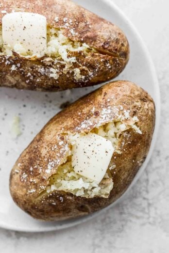 Two baked potatoes with butter on top