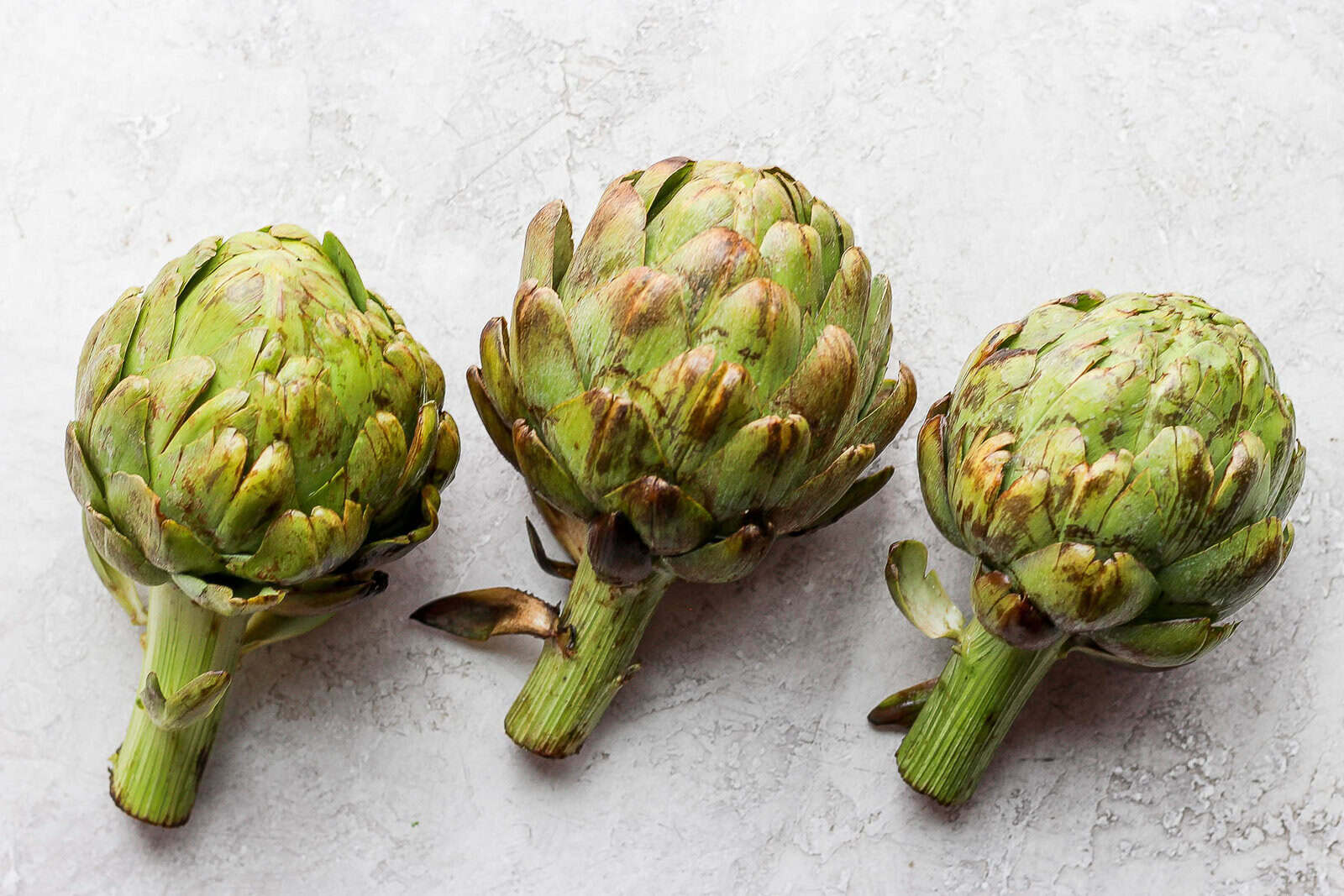 Three uncooked artichokes.