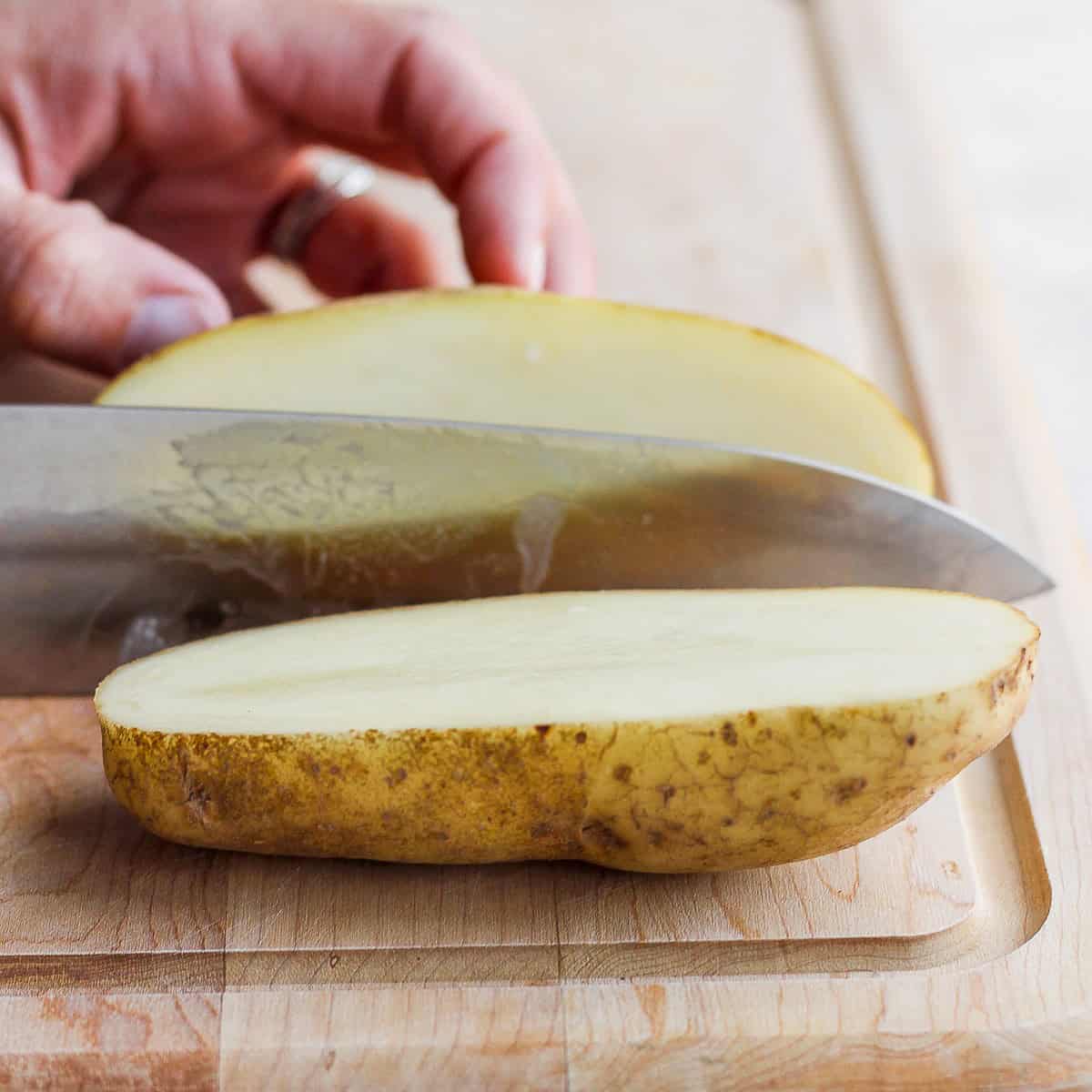 Slicing a potato in half, lengthwise.