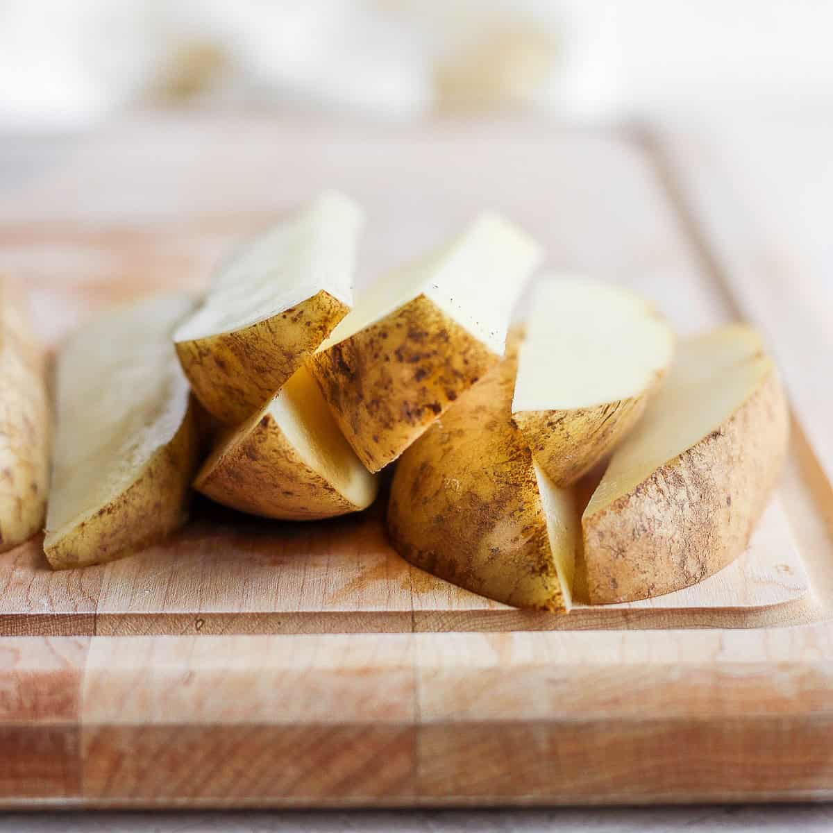 Potato wedges on a cutting board after cut.