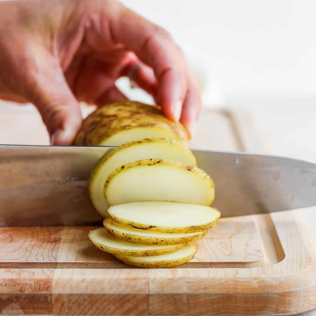 Cutting the potato in the same direction to create small slices.