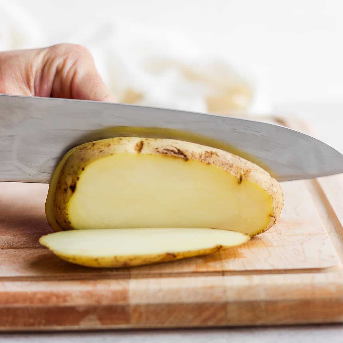 Cutting the potato lengthwise to make a flat surface.