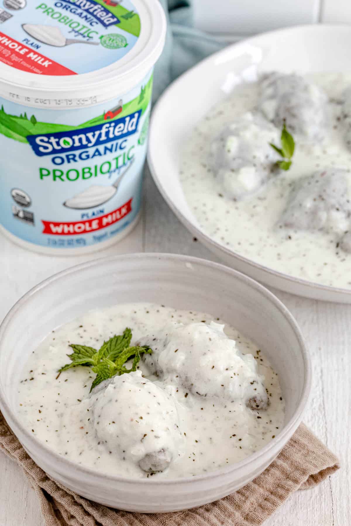 Kibbeh in yogurt sauce with large tub of Stonyfield yogurt in background