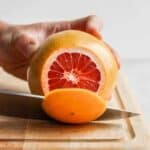 Slicing off top of grapefruit on cutting board