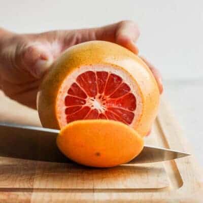 Slicing off top of grapefruit on cutting board