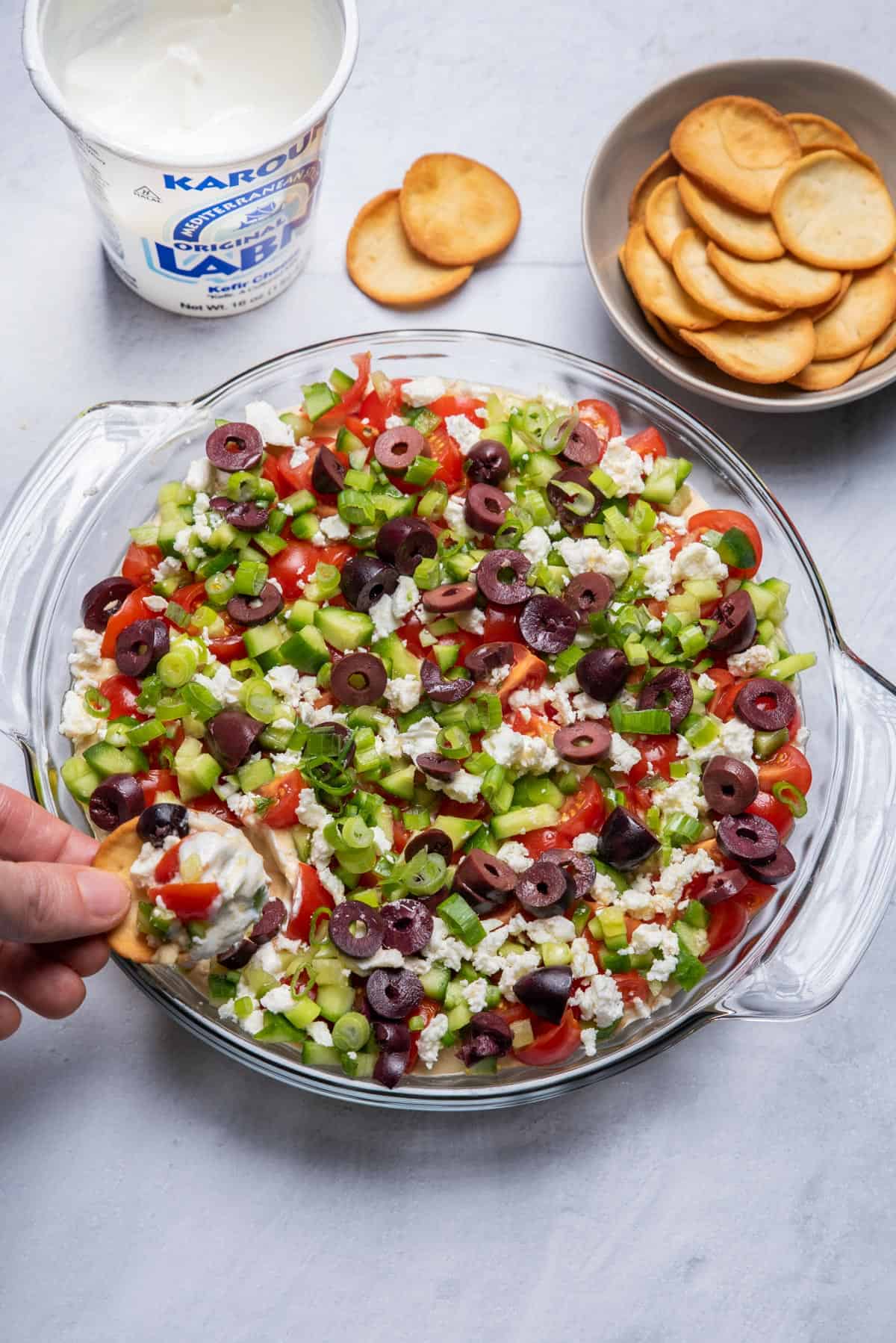 Pita chip going dipping into the 7 layer mediterranean dip