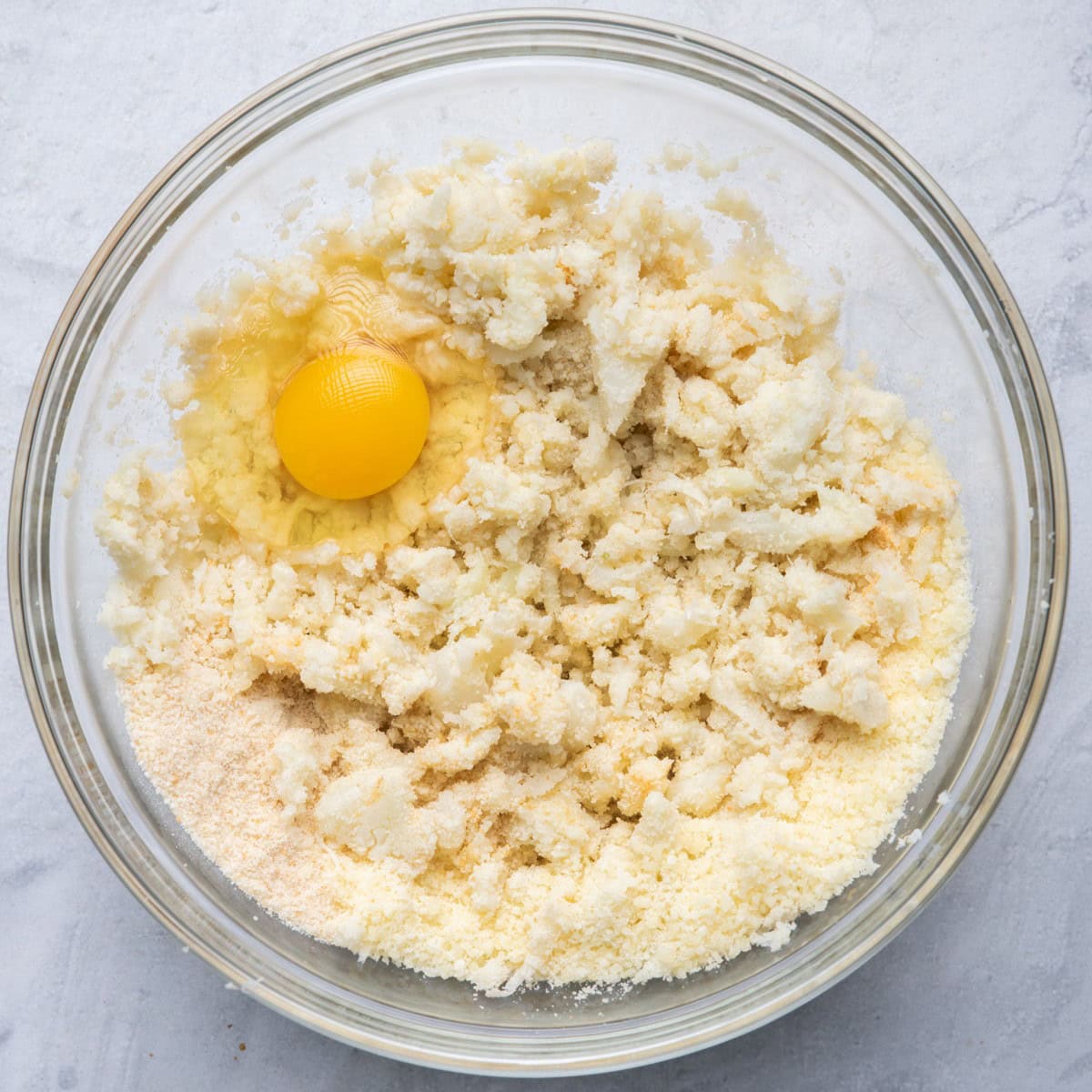 Cauliflower in bowl with other ingredients before mixing.