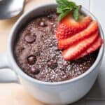 A chocolate mug cake with strawberries on top.