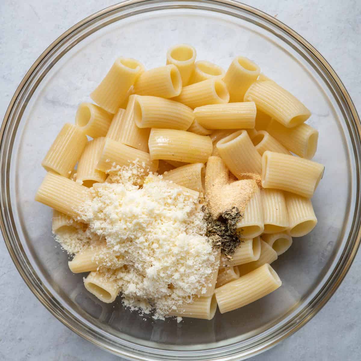 Pasta in bowl with olive oil, cheese, seasonings.
