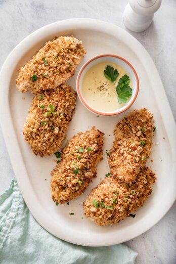 Pecan crusted chicken on a plate with honey mustard dipping sauce