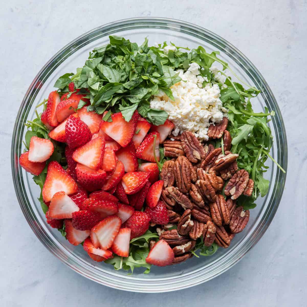 Salad ingredients after divided over arugula.