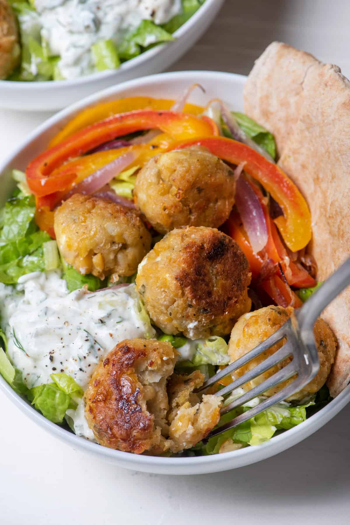 Close up shot of vegetarian gyro bowl with fork cutting into chickpea bites