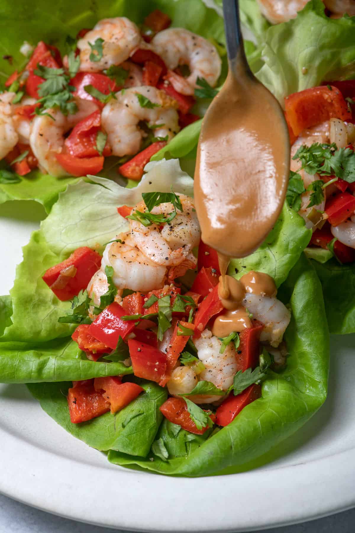 Spoon drizzling peanut sauce over shrimp lettuce wraps
