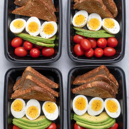 4 meal prep containers with the avocado, egg, toast and tomatoes