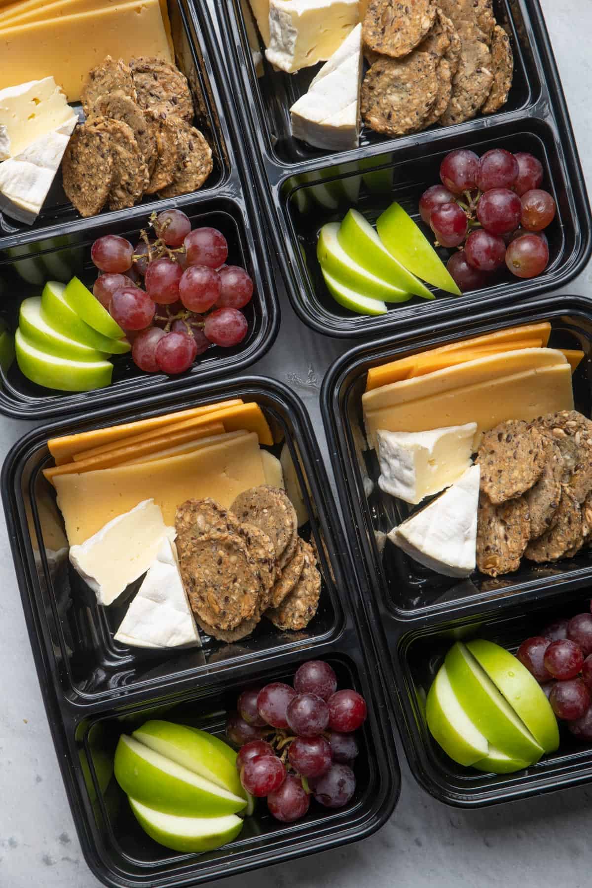 Meal prep containers with cheese, fruit and crackers