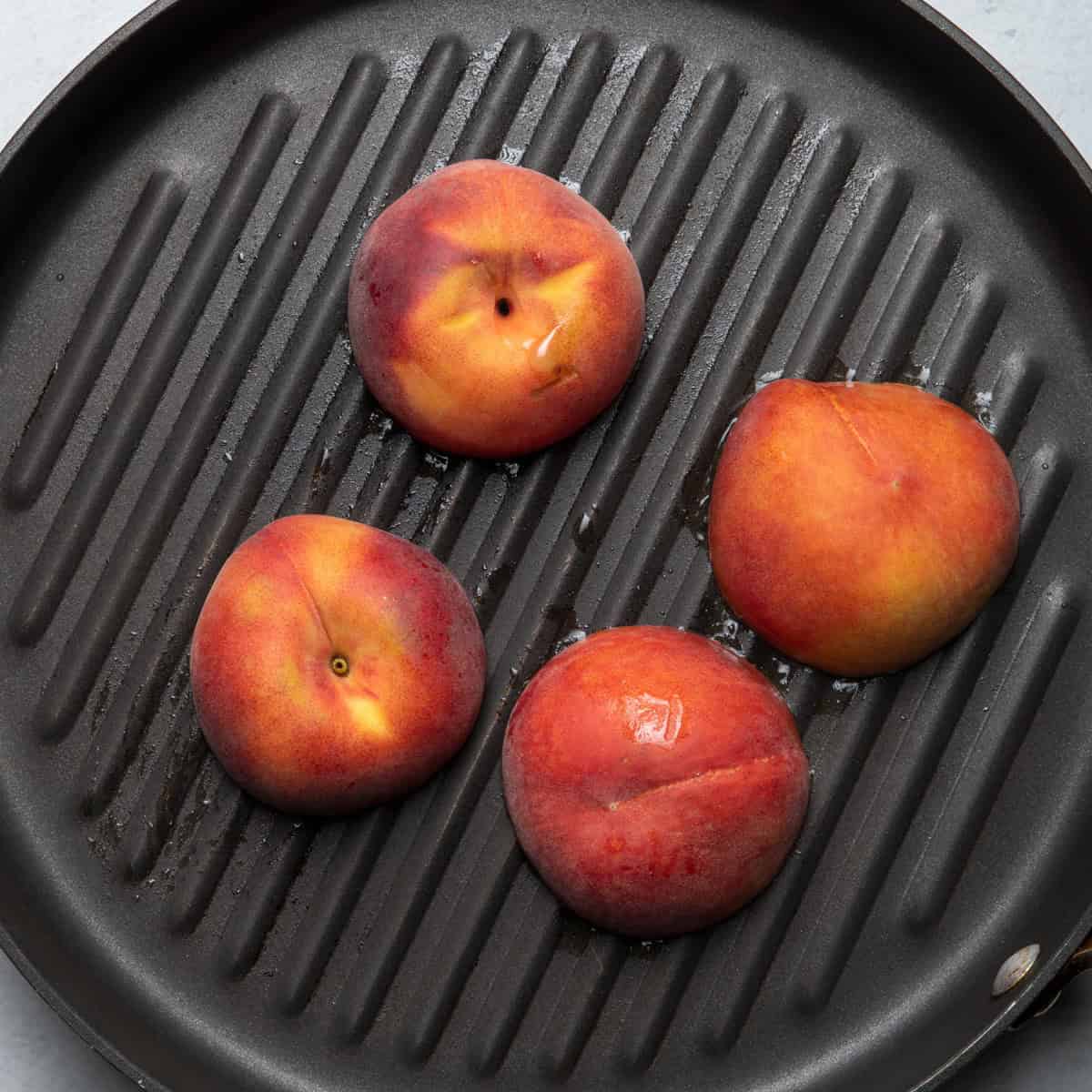 Peaches cut side down on grill pan.