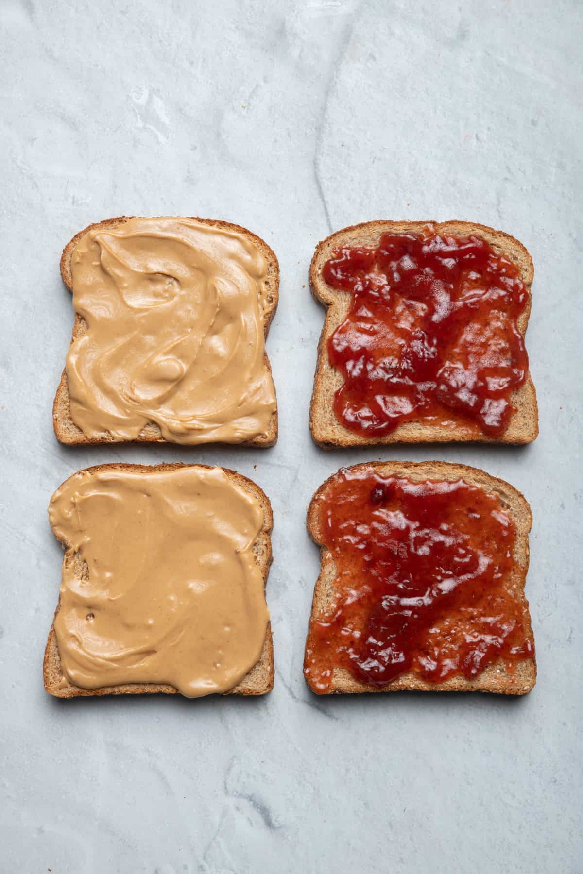 Four slices of bread with peanut butter and jelly on them