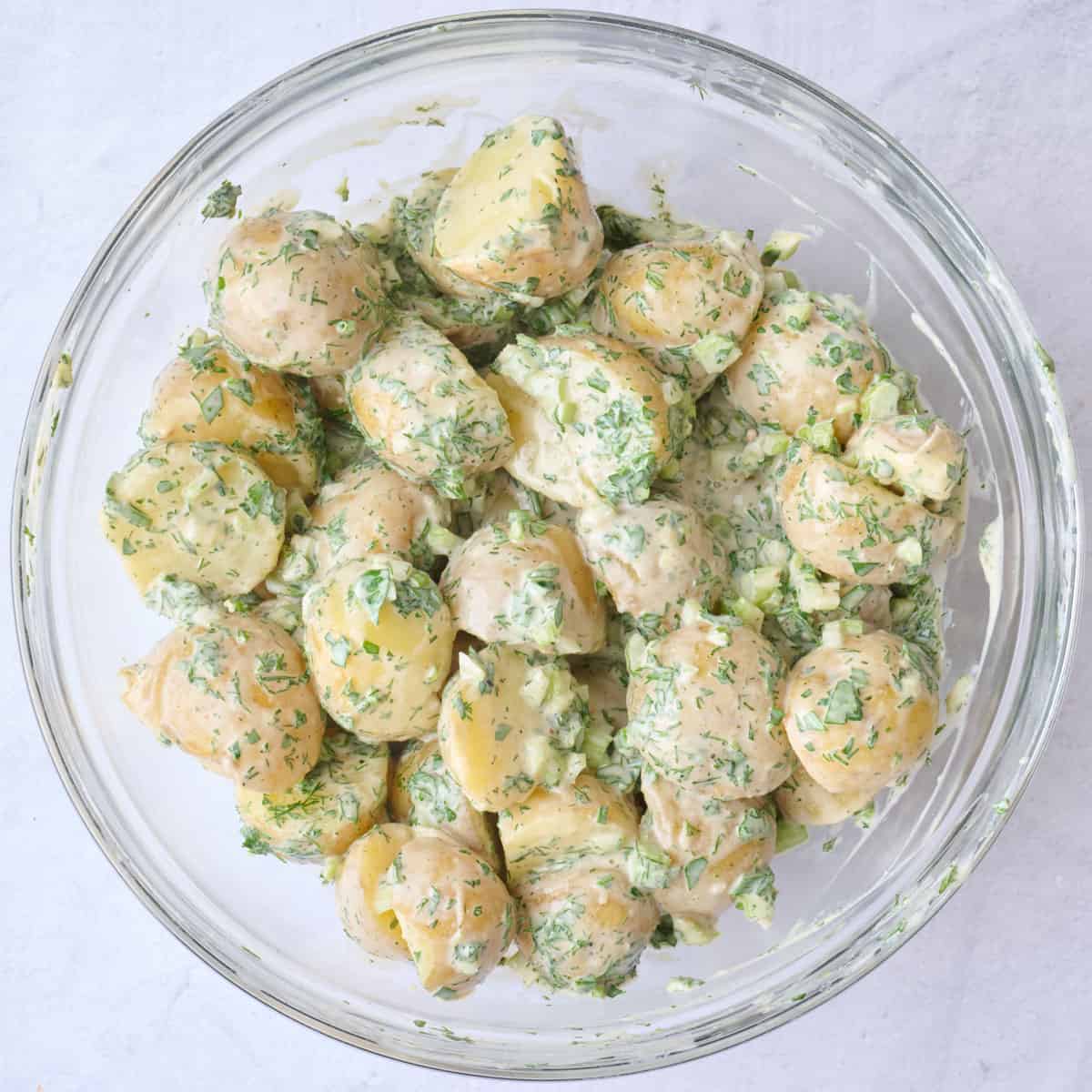 All of the tahini potato salad ingredients in a bowl after combining.